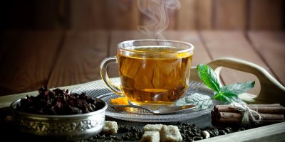 Skleněný šálek se zeleným čajem na dřevěném podnose