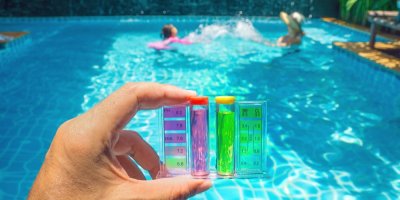 Ruka drží lahvičky, které kontrolují pH bazénu