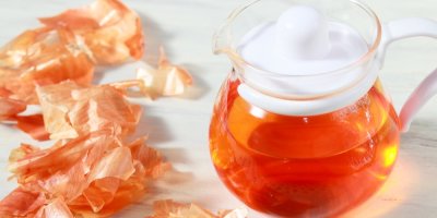 Zlatavý čaj z cibulových slupek ve skleněné konvici vedle hromádky slupek