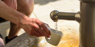 Muž si nabírá minerální vodu z lázeňského kohoutku.