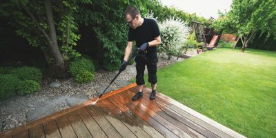 Muž čistí vysokotlakým čističem dřevěnou terasu