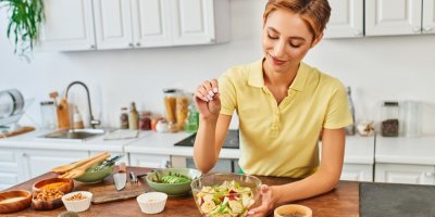 Žena dochucuje misku nakrájeného ovoce v kuchyni