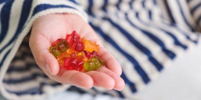 Dětská ruka držící gumové medvídky.