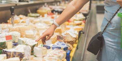 Žena ukazuje na modrý sýr na sýrovém pultu.