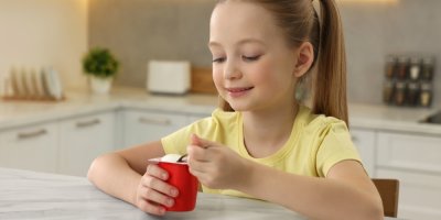 Dívka si pochutnává na jogurtu z kelímku.