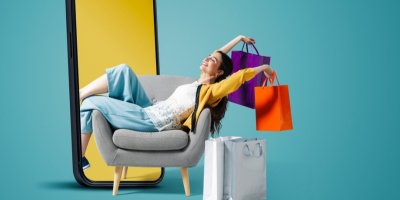 Žena sedí v křesle, drží nákupní tašky a vedle je velký telefon