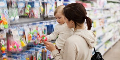 Matka drží dítě v náručí před regály v obchodě