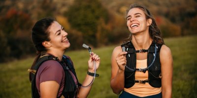 Dvě mladé ženy v přírodě s batohy na zádech s připojenými hydratačními vaky