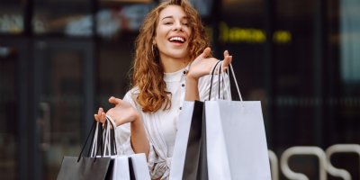 Mladá žena drží nákupní tašky a usmívá se