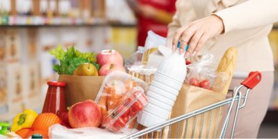 Žena dává mléko do plného nákupního košíku