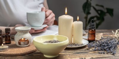 Aroma lampa s esenciálními oleji a hořící svíčky na dřevěném stole