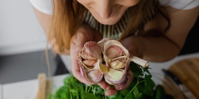 Žena drží rozpůlenou paličku česneku