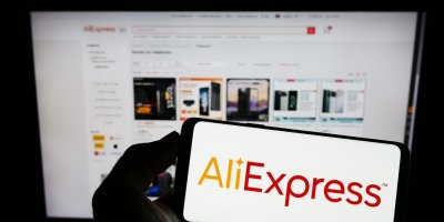 Logo AliExpressu v mobilu, v pozadí internetová stránka tržiště