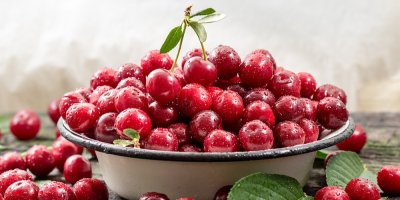 Bílá kovová miska s višněmi, kolem višně