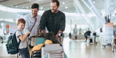 Rodiče s dítětem vezou kufry na letišti