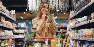 Žena se v obchodě usmívá a drží v ruce mobil