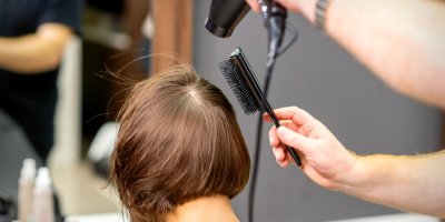 Ženě kadeřník fouká vlasy