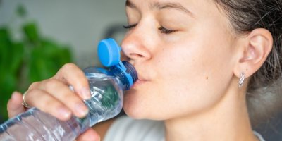 Mladá žena pije z pet láhve s neoddělitelným víčkem