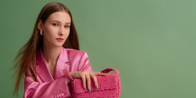 Žena s nazrzlými vlasy v růžovém kostýmku a s růžovou kabelkou