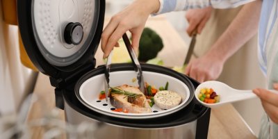 Žena vaří chutné ryby v multifunkčním hrnci