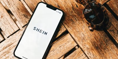 Smartphone ležící na dřevěném stole s otevřenou aplikací Shein