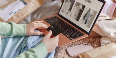 Postava drží v ruce kartu a nakupuje na internetu