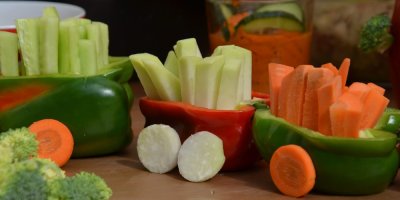 Vláček vytvořený z kousků zeleniny, vagóny jsou z paprik a v nich jsou naskládané kousky mrkve, okurek a kedluben.