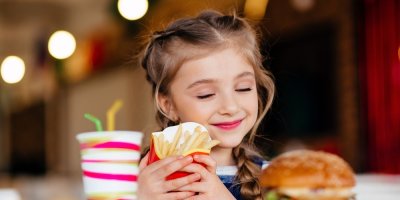 Holčička drží v ruce hranolky a usmívá se