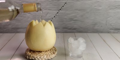 Nalévání bílého vína do vydlabaného melounu s brčkem