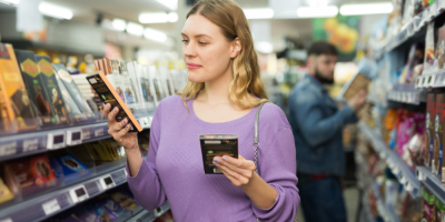 Žena si prohlíží obaly dvou čokolád v obchodě