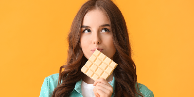 Žena si před obličejem drží tabulku bílé čokolády