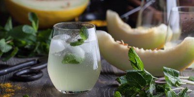 Melounová limonáda s ledem a mátou, v pozadí žlutý meloun