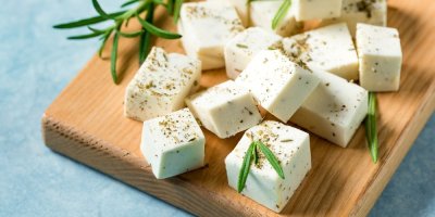 Sýr nakrájený na kostičky na dřevěném prkénku