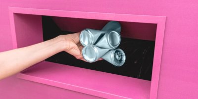 Žena vhazuje plechovky do kontejneru