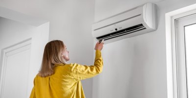 Žena zapíná ovladačem zabudovanou klimatizaci