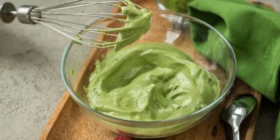 Skleněná mísa s našlehanou zelenou pěnou a kovovou metličkou