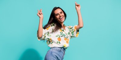 Žena v košili a džínech radostně tančí. 