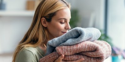 Žena si čichá k poskládaných svetrům, jeden modrý a druhý červený