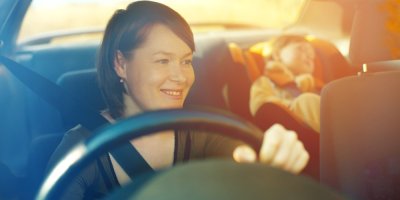 Žena řídí a za ní spí dítě v autosedačce