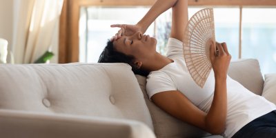 Žena ovívající se vějířem na gauči