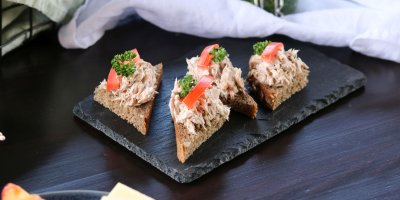 Malé chlebíčky s pomazánkou ozdobené rajčátkem a petrželkou