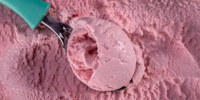 Lžíce nabírající růžovou jahodovou zmrzlinu