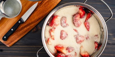 Jahody v hrnci zasypané krystalovým cukrem