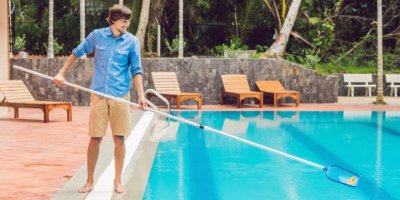 Muž čistí bazén síťkou