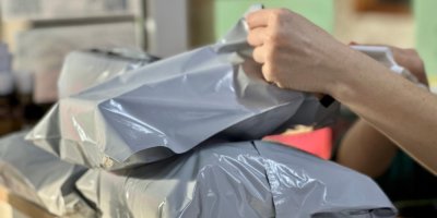 Záběr na rozbalování zásilek v šedých plastových pytlích