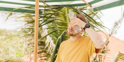 Muž se ochlazuje lahví s vodou