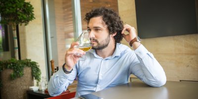 Muž sedí u stolu a pije whisky