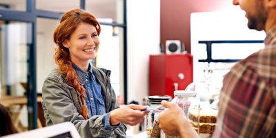 Prodavačka s úsměvem vrací peníze zákazníkovi. 