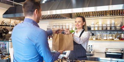 Muž přebírá v restauraci tašku s jídlem