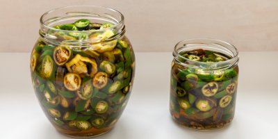 Dvě otevřené zavařovací sklenice s nakládanými papričkami